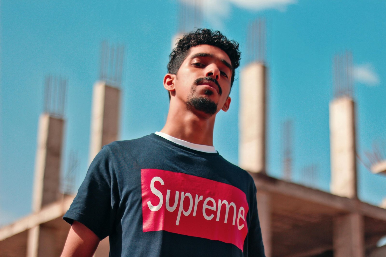Portrait of a confident young man in Riyadh with unfinished construction in the background.